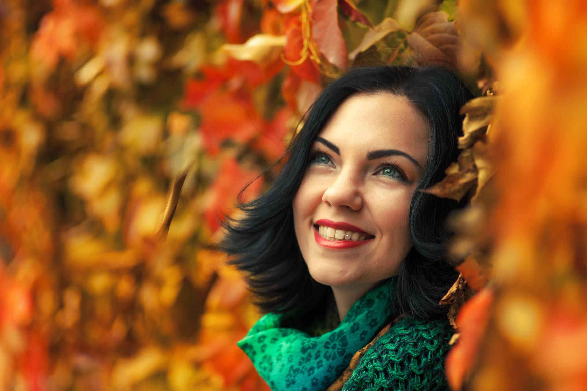 Kobieta w jesiennym makijażu leżąca w kolorowych liściach 